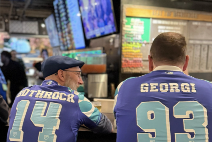 Two soccer fans enjoy a soccer match on the big screens while enjoying pints at the bar top at Flatstick Pub - Spokane